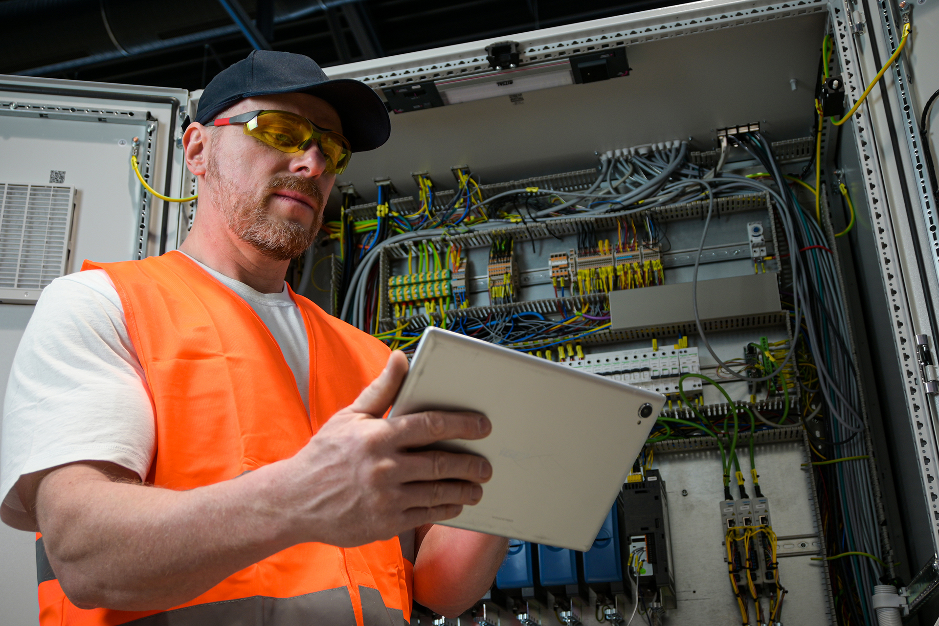 Technician inspecting electrical control equipment for asset lifecycle planning and condition assessment.