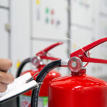 Building manager inspecting fire extinguishers as part of building compliance and fire safety management.