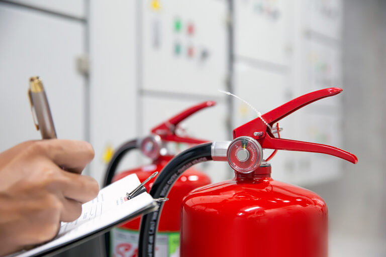 Building manager inspecting fire extinguishers as part of building compliance and fire safety management.