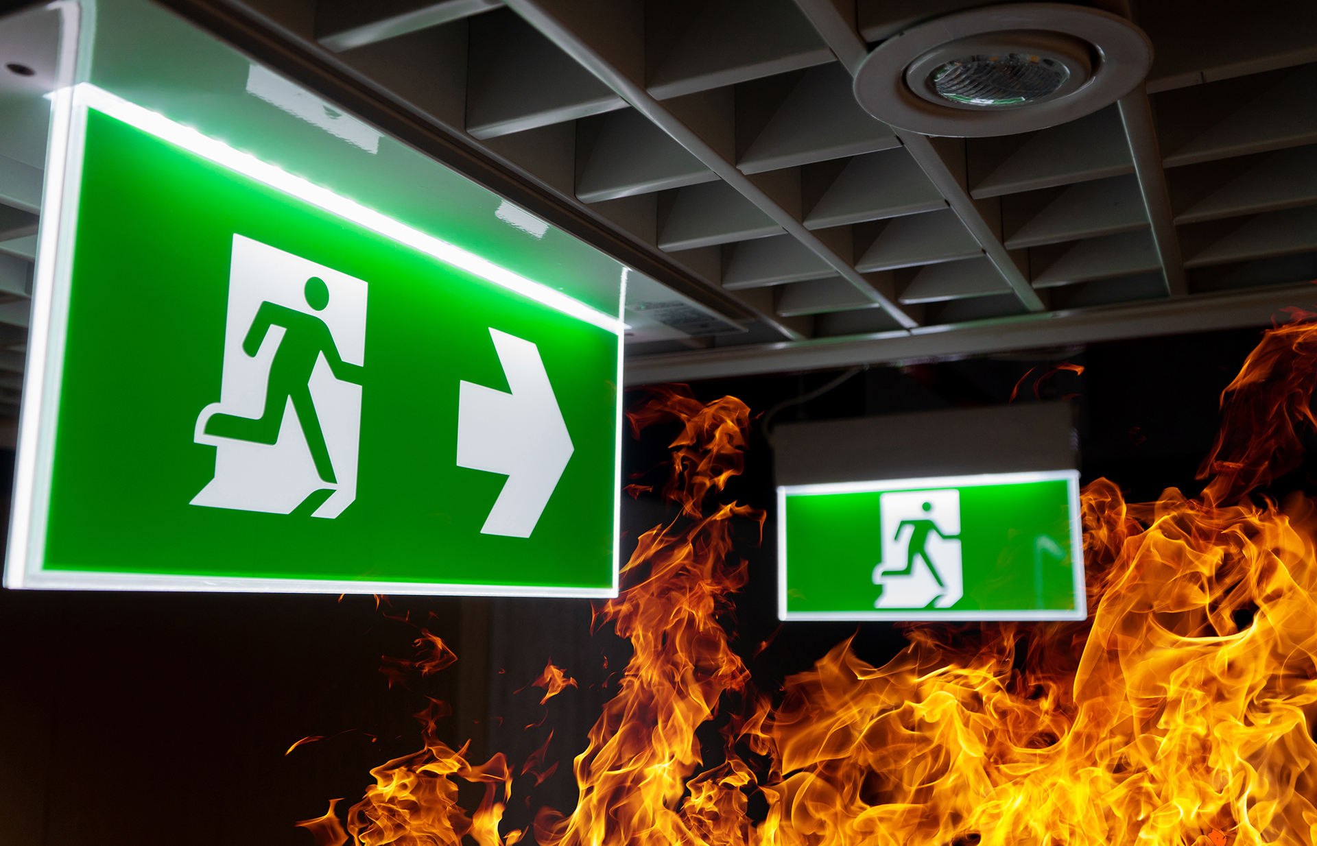 Emergency exit sign with visible fire illustrating building emergency preparedness and evacuation planning.