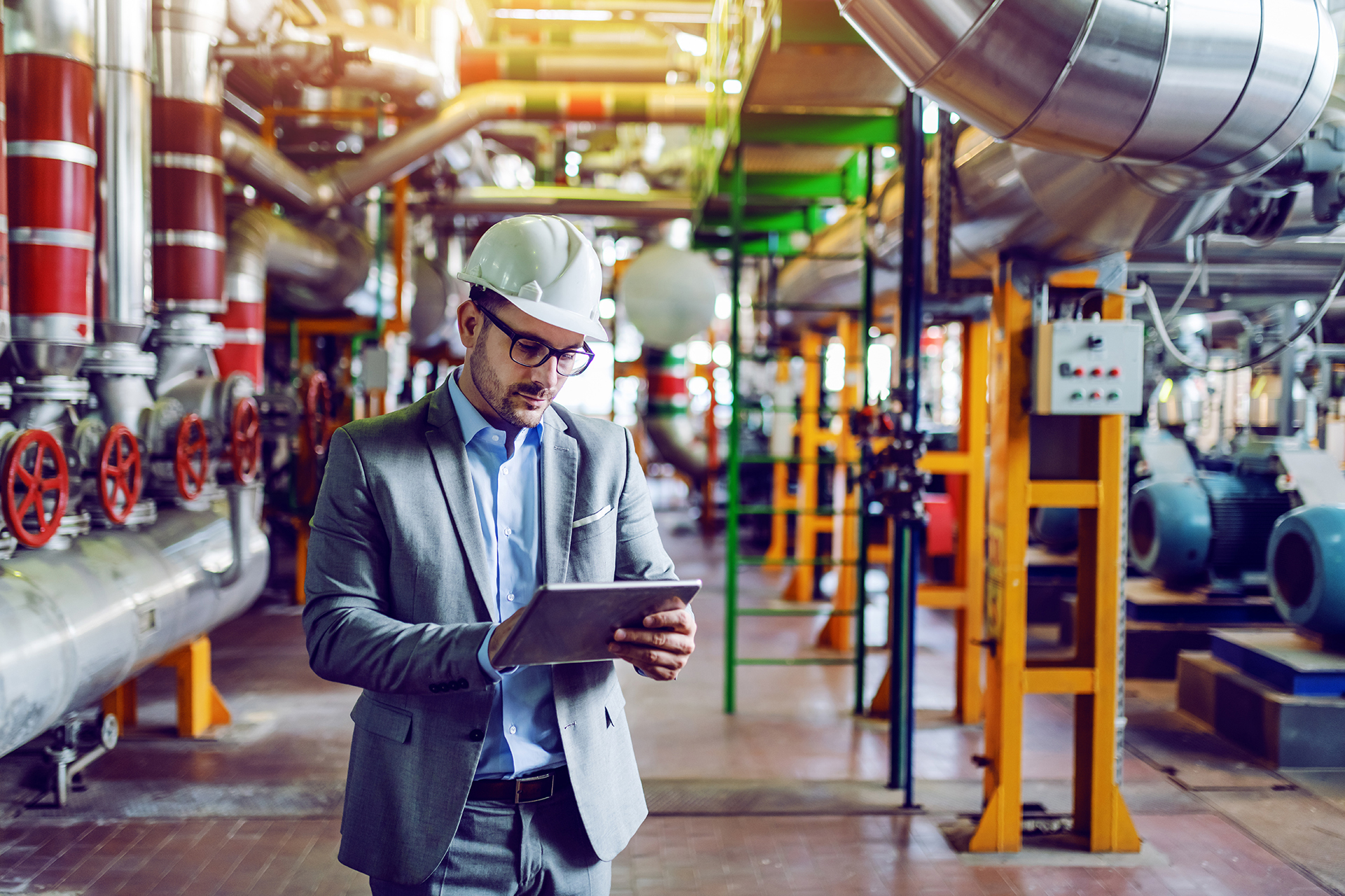 Building professional inspecting mechanical plant and critical infrastructure in a commercial building plant room.
