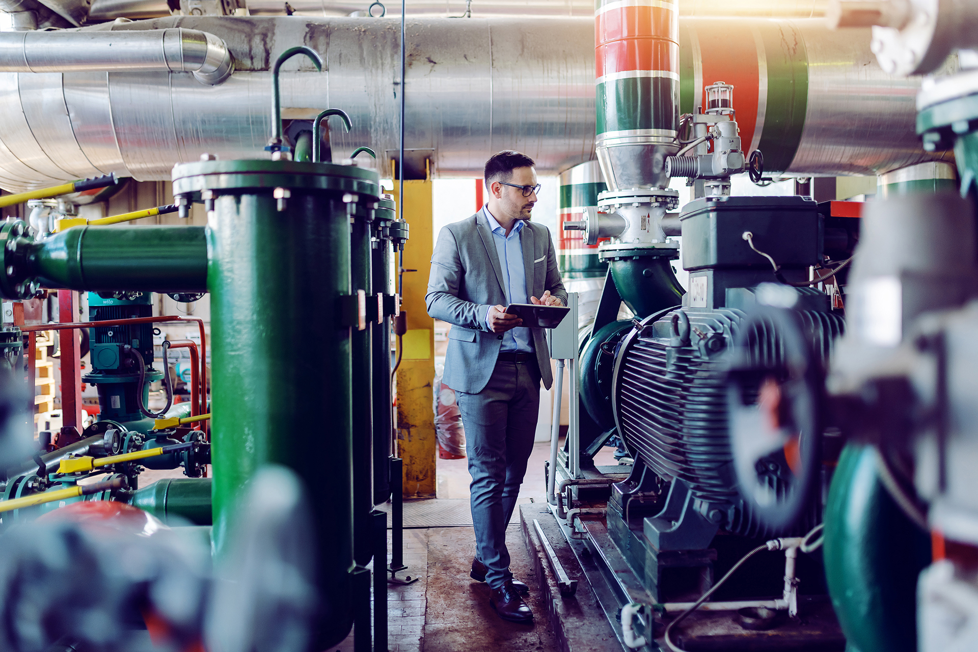 Commercial building professional inspecting mechanical plant room equipment and building services infrastructure.