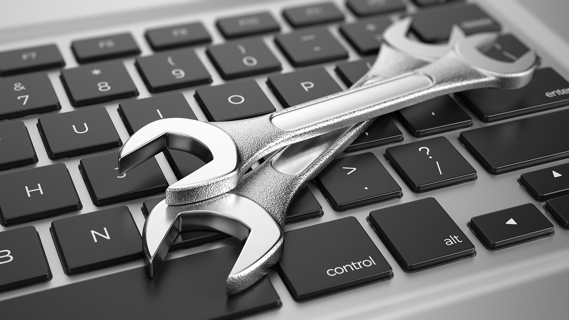 Spanners on a computer keyboard representing facility governance, maintenance management, operational control, and building oversight.