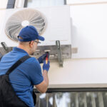 Technician performing maintenance on an external commercial HVAC air conditioning unit as part of a building maintenance governance program.